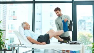 یک فرد مسن روی تخت، در حال انجام فیزیوتراپی